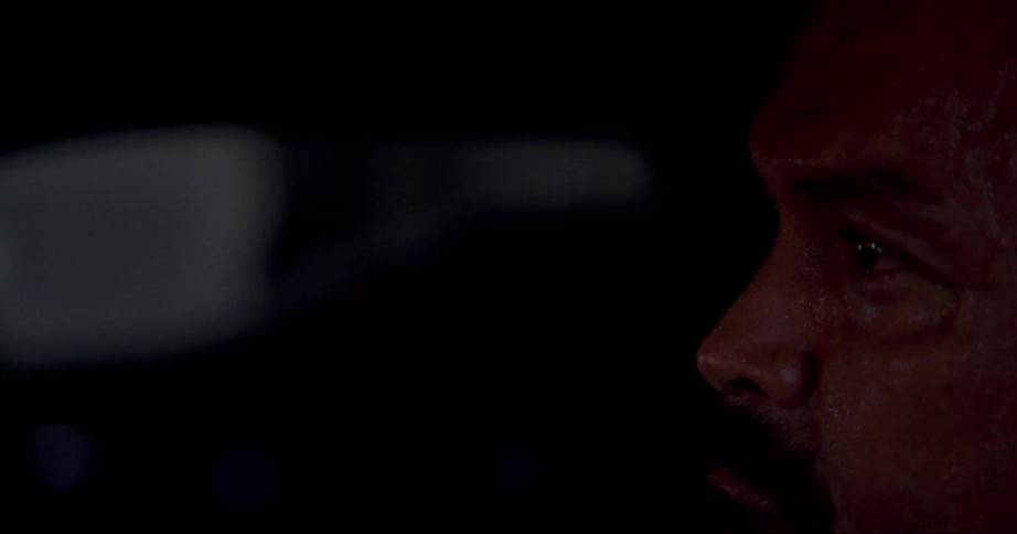 A man is looking forward and light is reflecting on his face