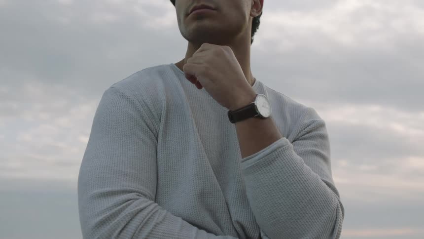 Man stands outdoors looking around under cloudy sky