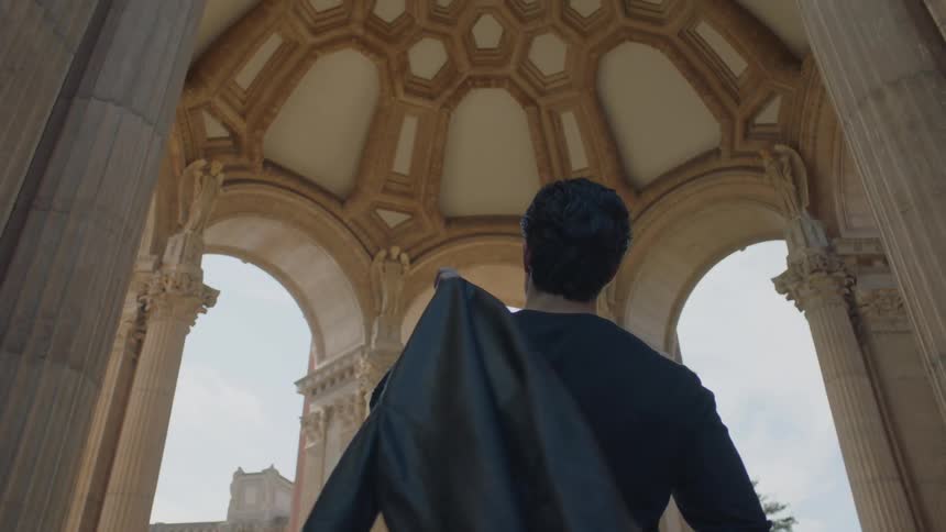 A male standing outside under a building with a decorative ceiling and columns