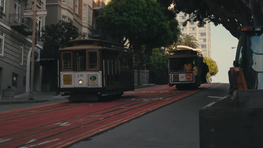 Trolley cars pass by each other in front of apartment buildings