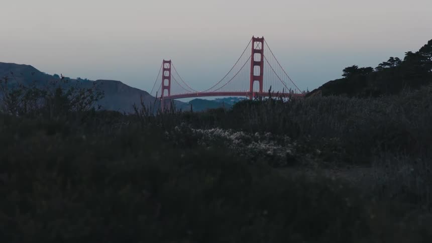 Red suspension bridge between mountains at sunset