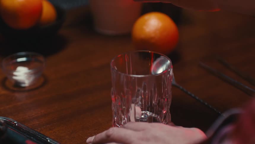 Close view of the hands of a man preparing some type of mixed beverage at a counter