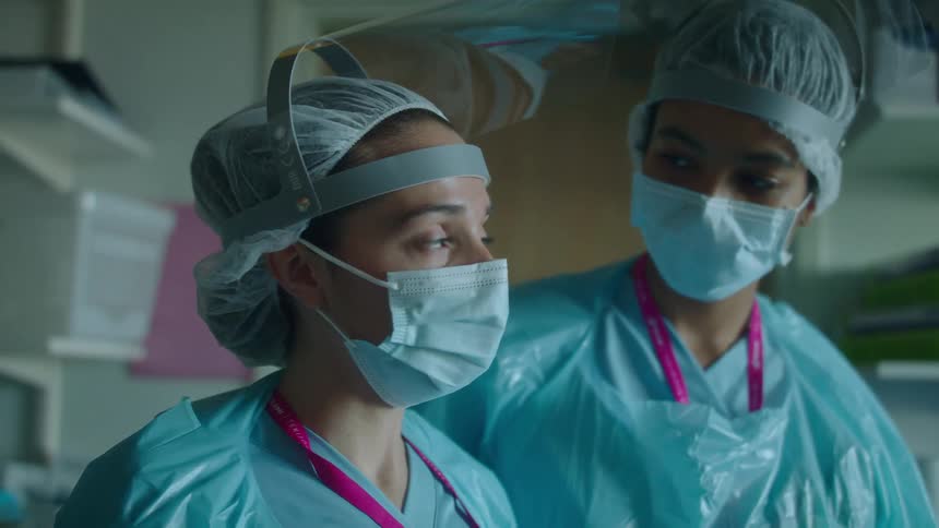 One nurse comforts another nurse in a hospital room during the day