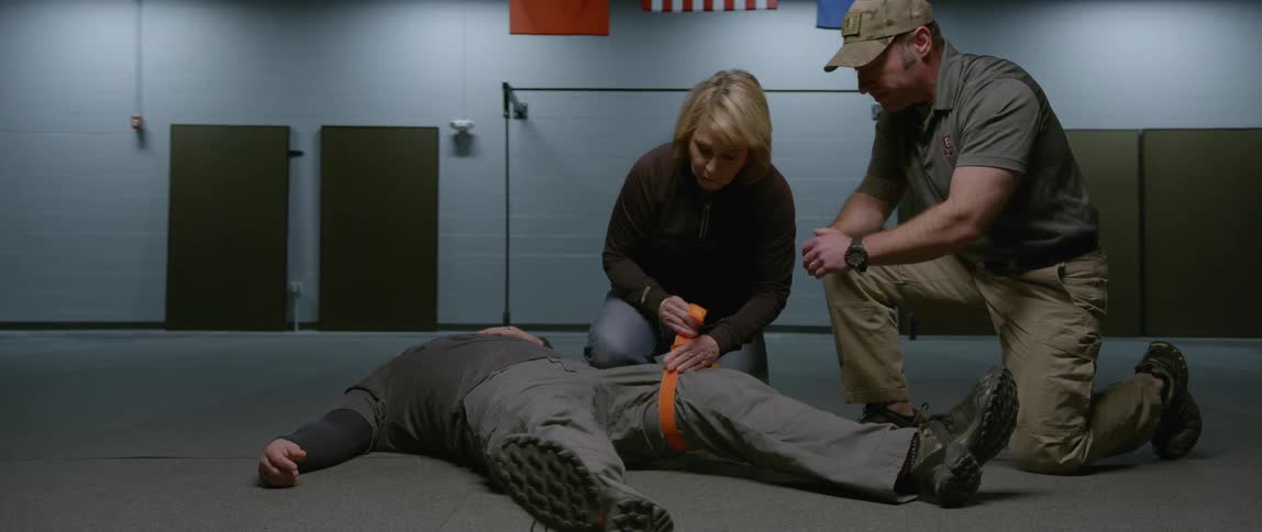 A woman wraps a tourniquet around a man's leg