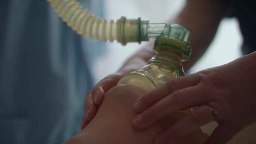 Nurse practicing how to place an oxygen mask over a mannequin in a hospital
