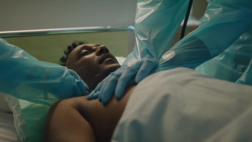 Doctor wearing protective clothing performing cpr on a patient on a hospital bed