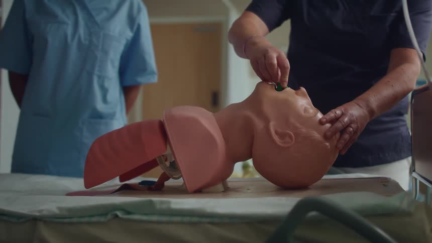 Someone is practicing a medical procedure by placing a tube into the mouth of a dummy