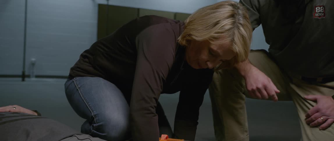 A woman demonstrates applying a tourniquet to a man's leg