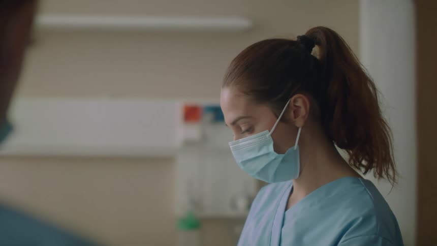 Nurse wearing blue disposable face mask working on a hospital room