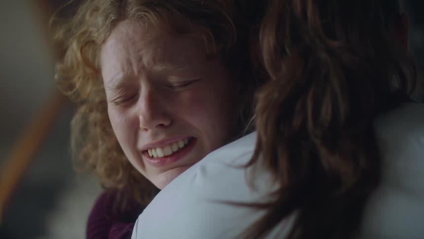 A woman cries on another womans shoulder as they hug