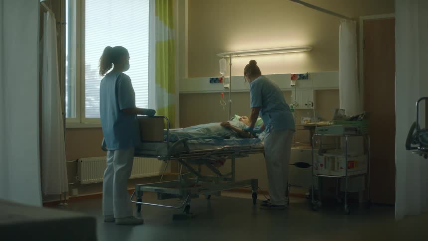 Nurses help a man move his arm up and down while he lies in bed