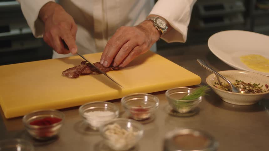 A chef cutting meat in a kitchen