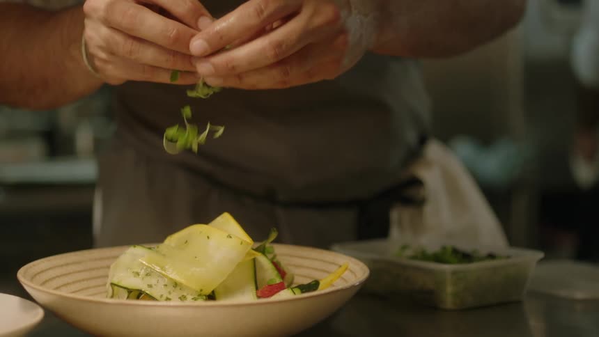 A chef is putting garnish on food