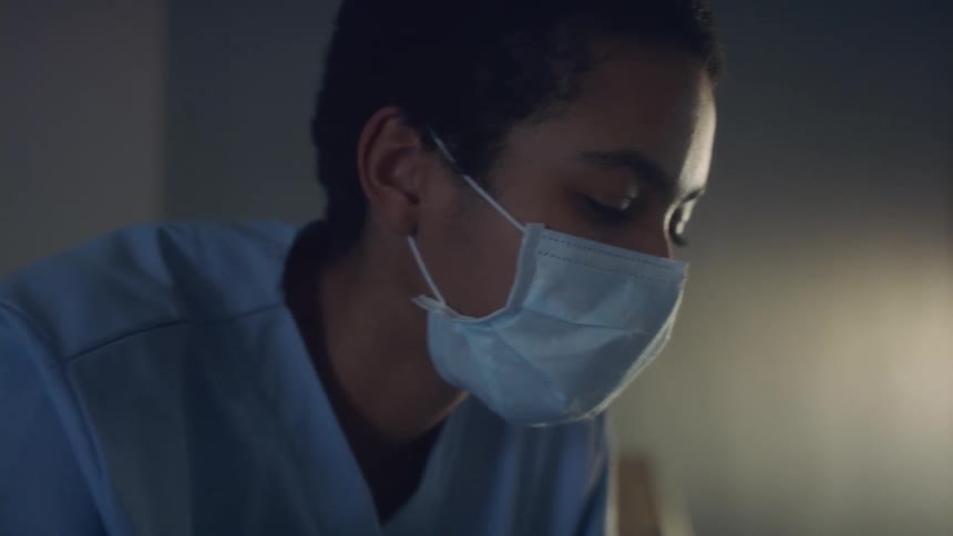 Anxious nurse withshort hair mask and scrub operates in hospital room