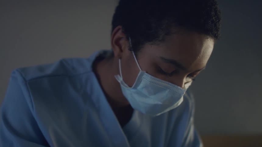 Young woman with short hair wearing a blue disposable face mask inside a room