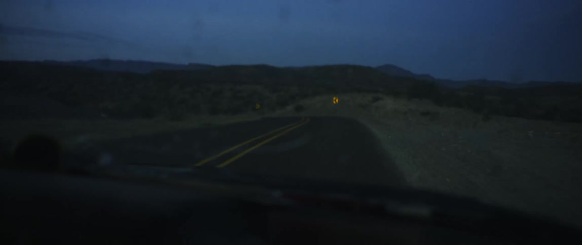 Vehicle travels on country road taking a bend at dusk