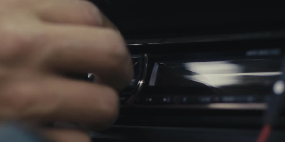 Mans hand inserts a cd into the cd player in car