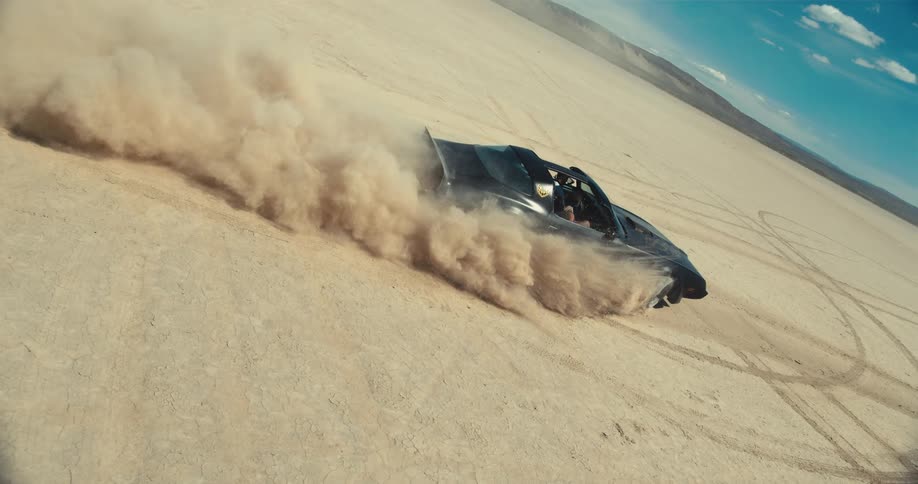 A t top sports car kicks up sand and creates tracks in the desert
