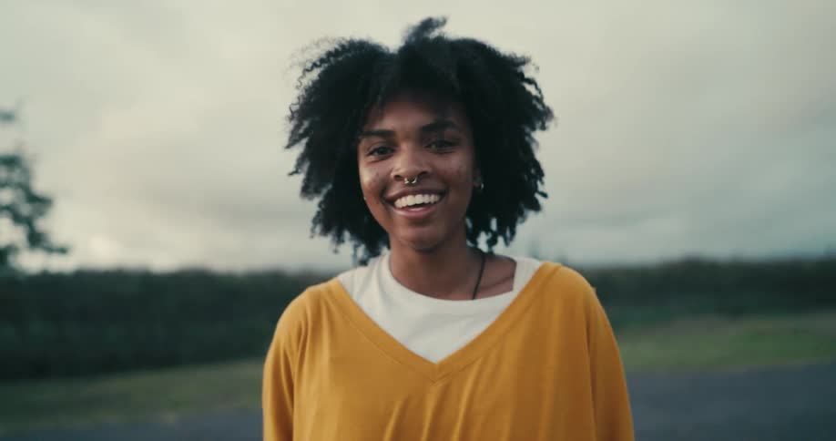 A woman laughing outside on a cloudy day