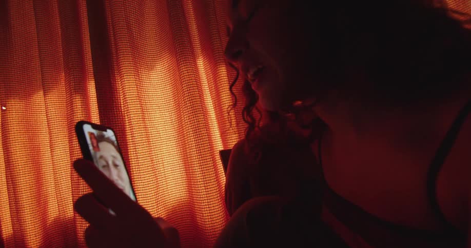 A woman is having a video chat with a man on a smartphone while indoors during the daytime