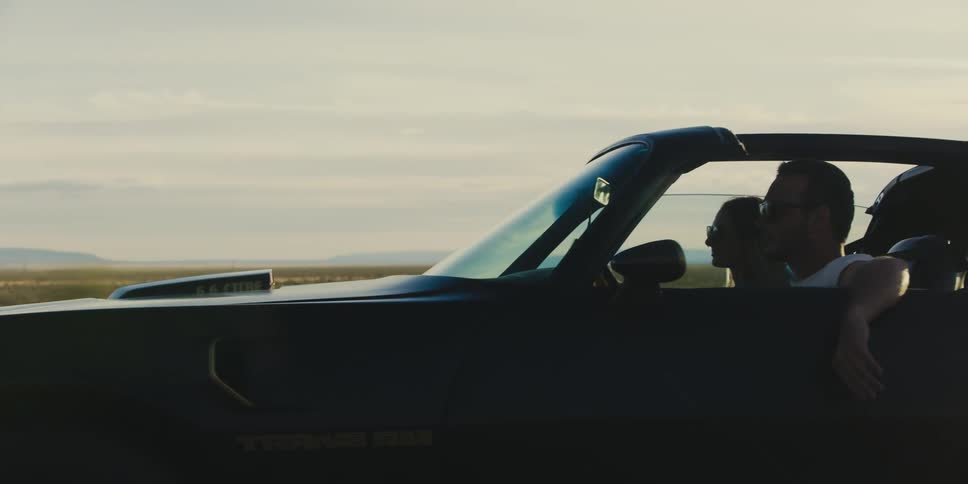 A male and female in a car driving on a road outdoors