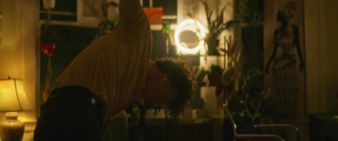 A man in a room dancing with a wall and windows in the background