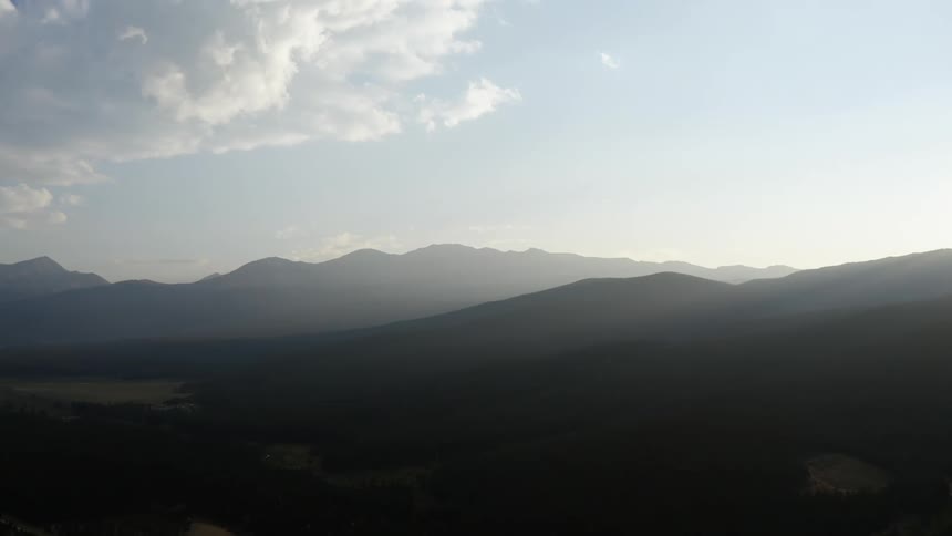 A landscape with hills with a mountain range the sky and clouds in the background