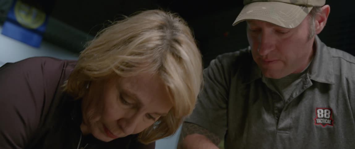 A woman and man look down working on something
