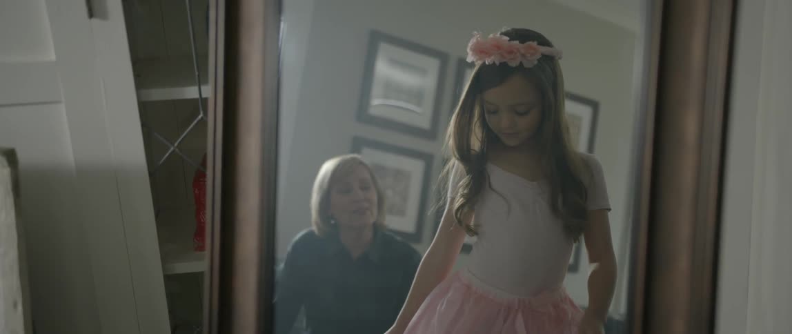 A girl in a pink tutu dances in front of a mirror
