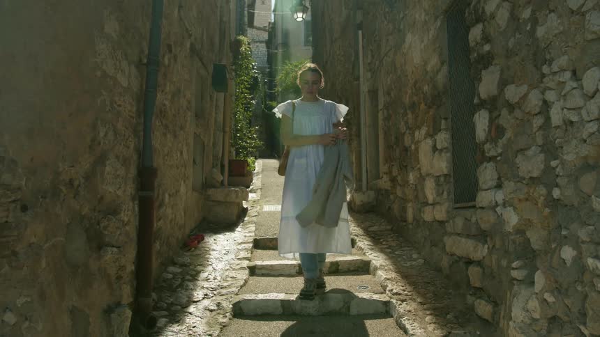 A woman walks down a narrow alley of an old city