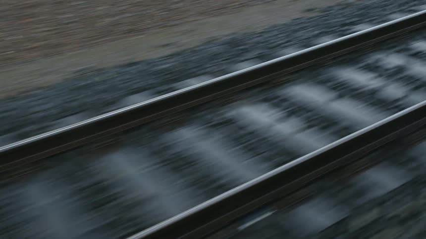 A static shot of railroad tracks as a train moves