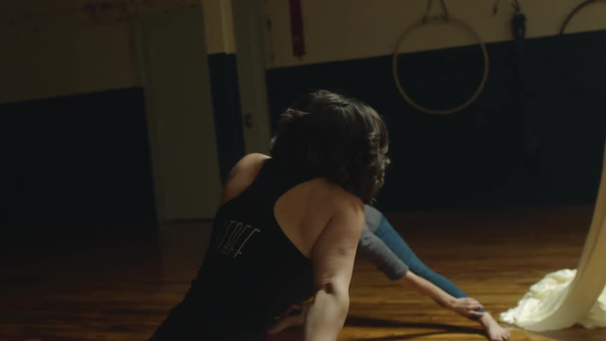 Three female dancers are stretching inside a dance studio at night