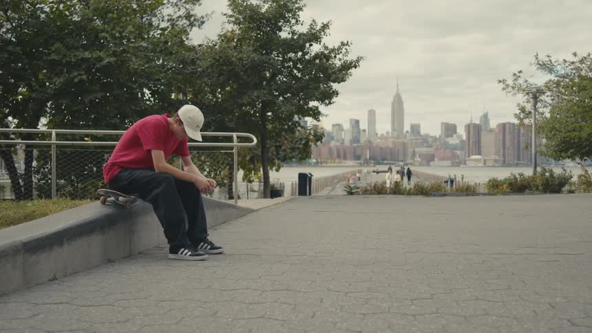 A man sitting outdoors on a skateboard