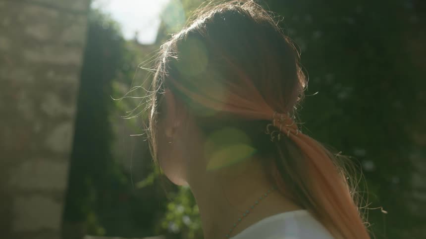 A woman standing outside near buildings on a sunny summer day