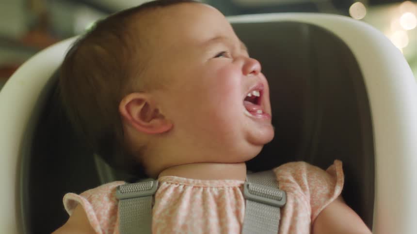 A baby crying in a baby chair