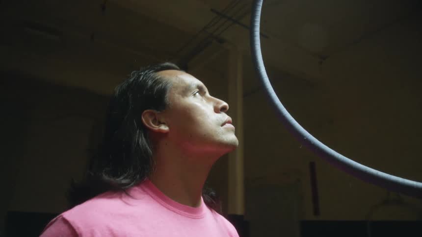 A man is staring up at a metal ring as he stands in a room