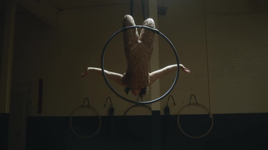 Woman hangs on hoop rotating in mid air in gym