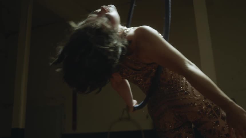 A woman in a room spinning on a hoop and rope with a wall in the background