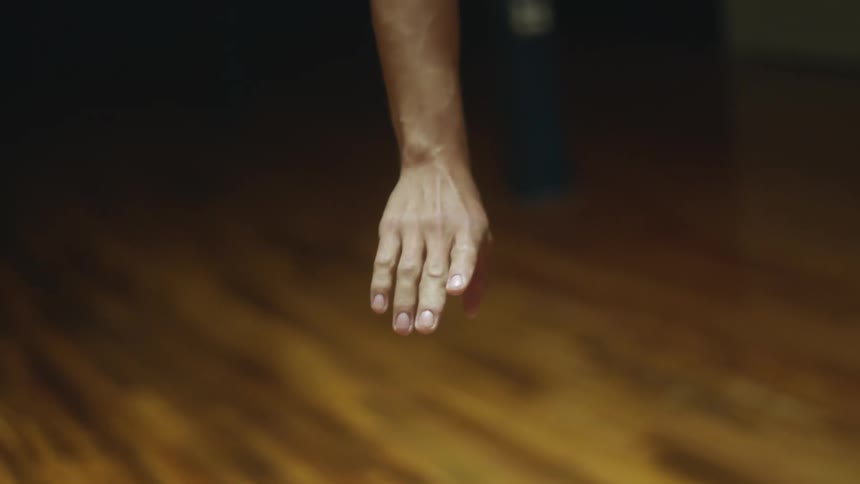 A dancer gracefully moves their arm and hand as they stand on a stage