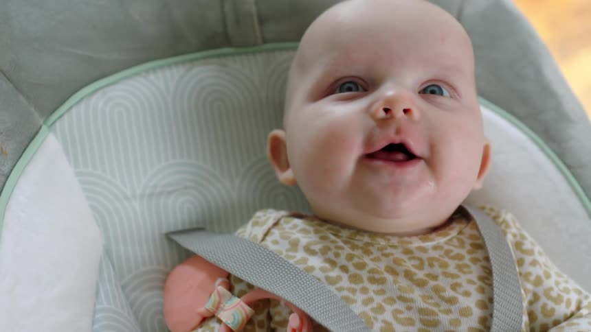 A baby is laying down sneezing