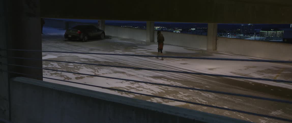 Woman walking through a nearly empty parking garage at night