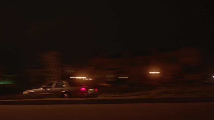A vehicle speeds past a neighborhood at night