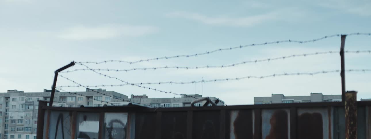 Barb wire is on a fence before the city