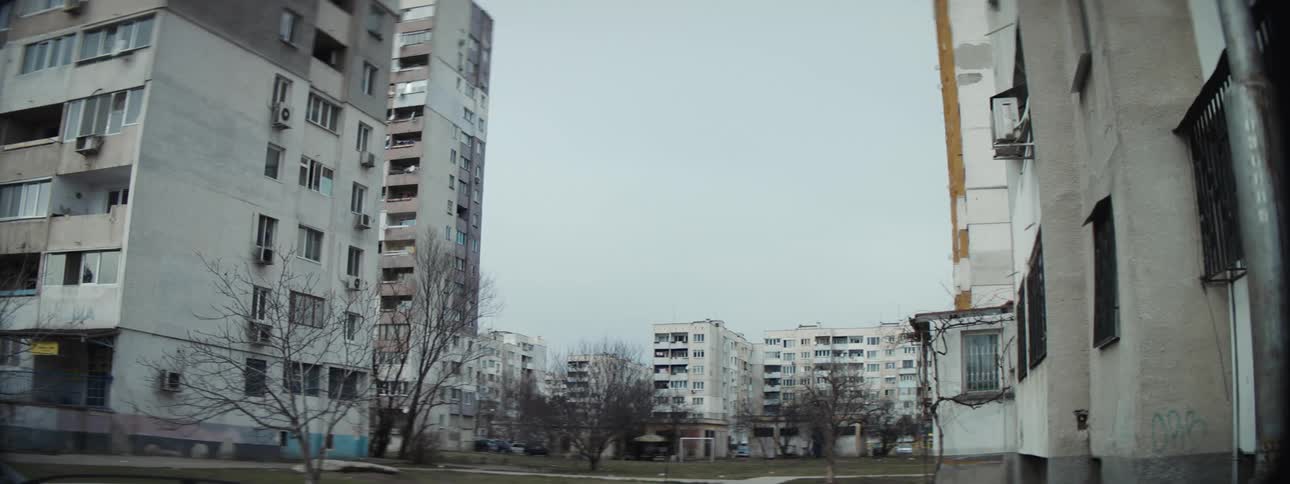 A neighborhood with buildings and trees with the sky and clouds in the background