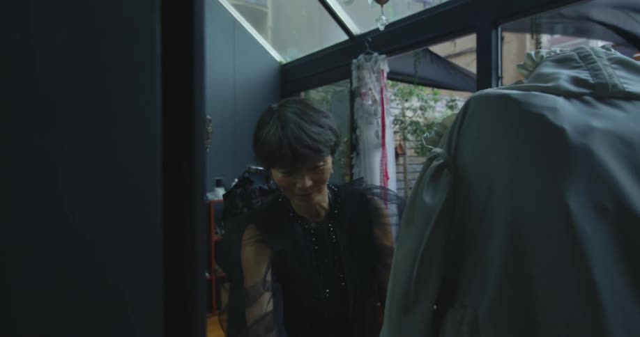 A woman is adjusting a dress that is on a mannequin