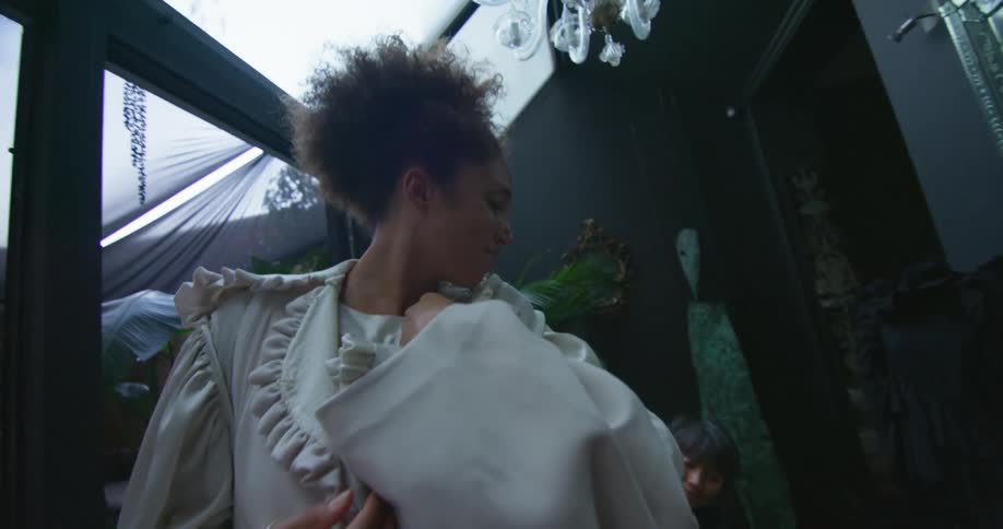 One woman turns while another adjusts her clothes