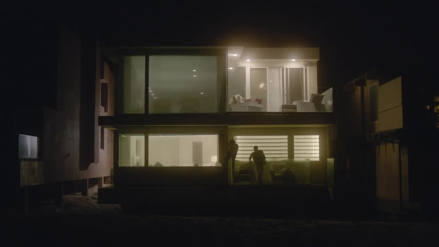 A silhouette of two people sneaking out of a house