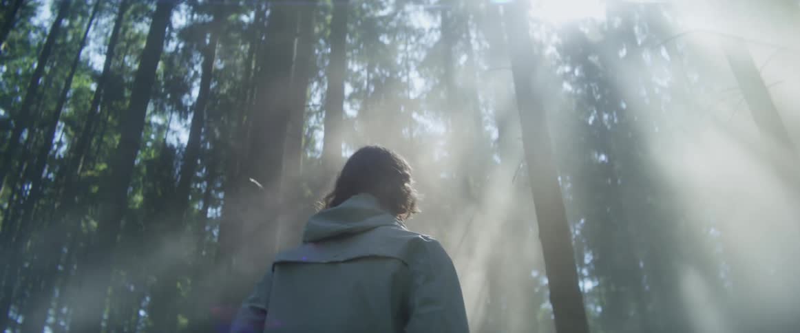 A man is hiking through the fog filled forest