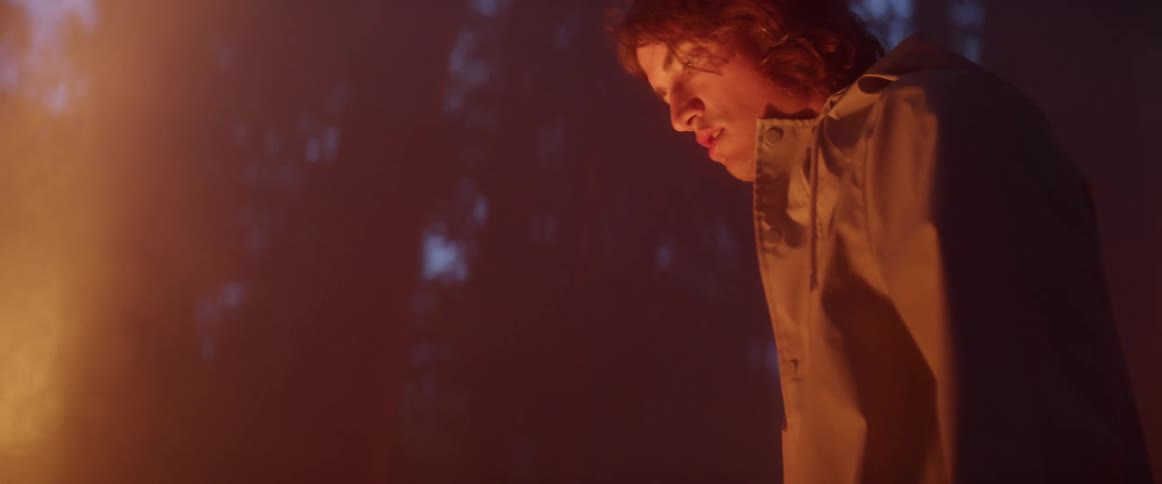 A man is looking down at a light in the forest