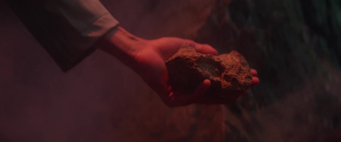 A person lifts a rock in the cave and a light flashes